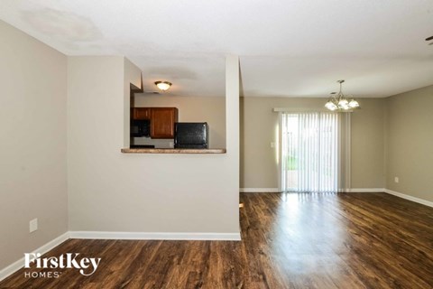 A spacious room with wooden floors and a television mounted on the wall.