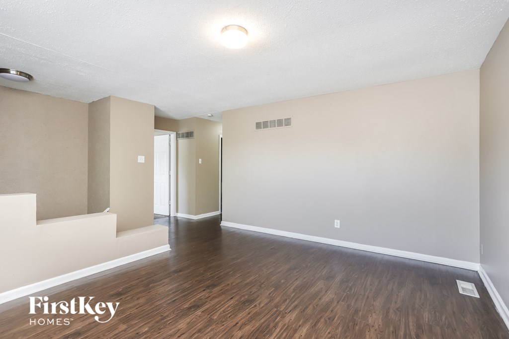 an empty living room with wood flooring and white walls
