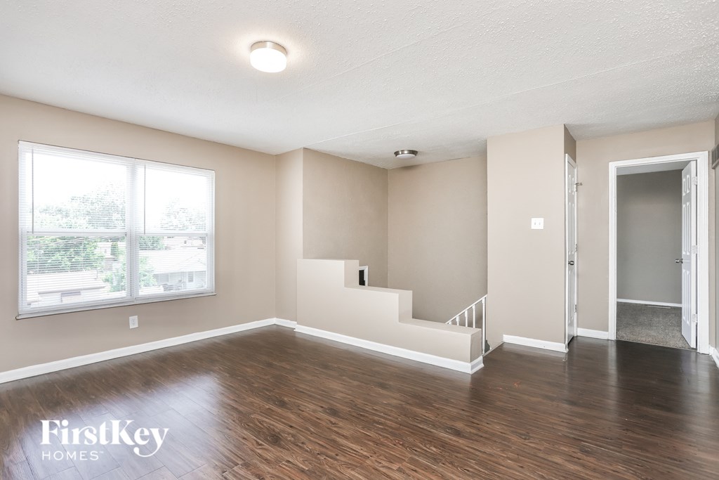 an empty living room with wood flooring and a staircase