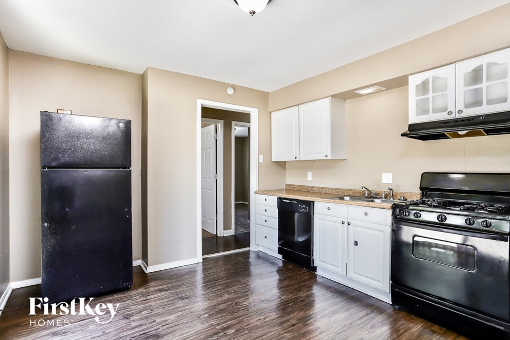 an empty kitchen with black appliances and white cabinets