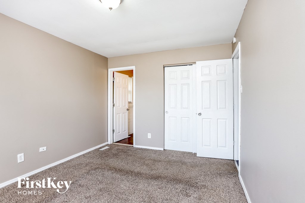 a bedroom with carpet and two closets and a door to a hallway