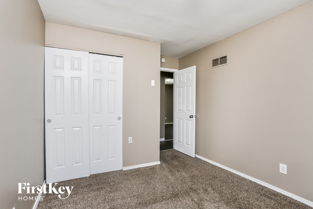 a bedroom with two closets and two doors and a carpeted floor