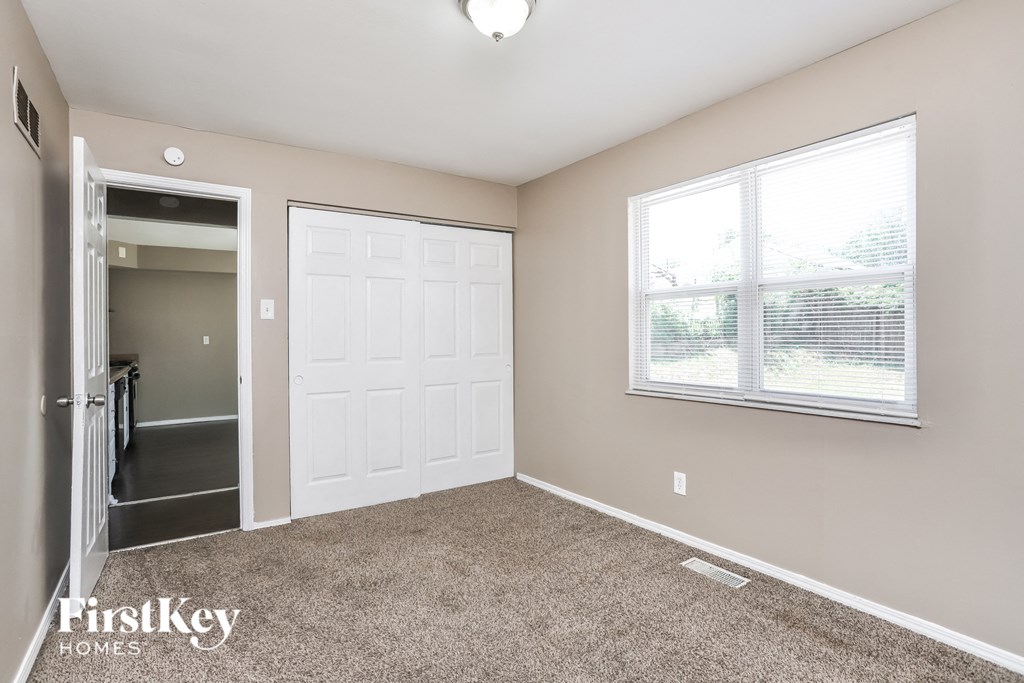 a room with carpet and a white door and a window
