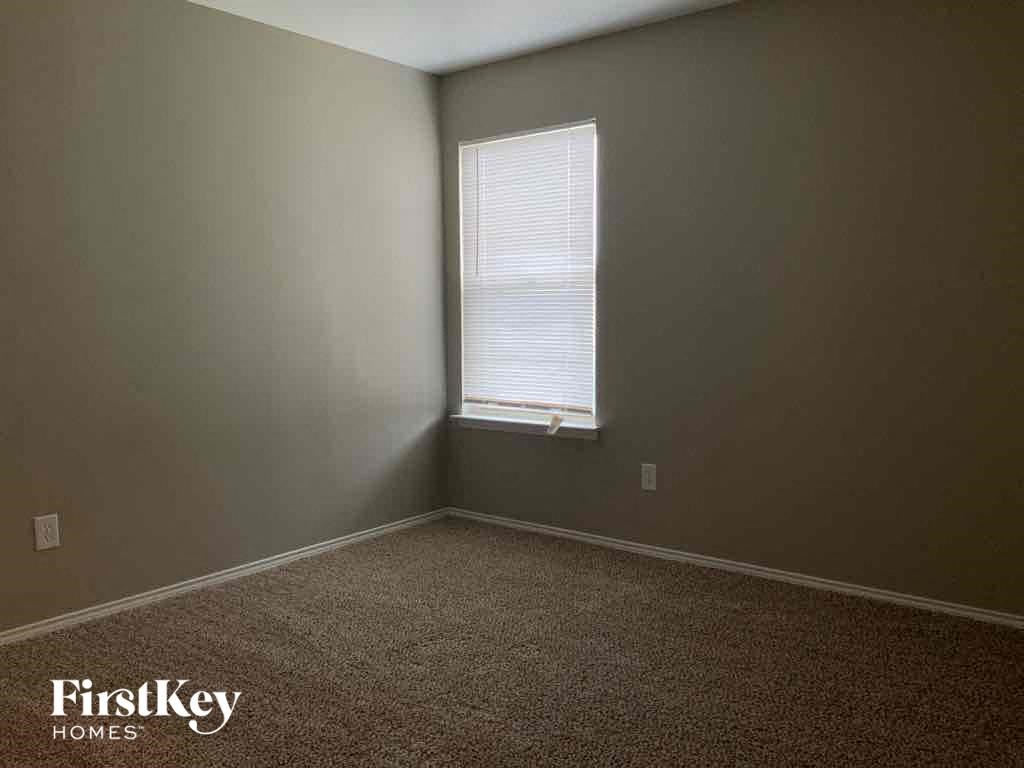 a bedroom with a window and a carpeted floor