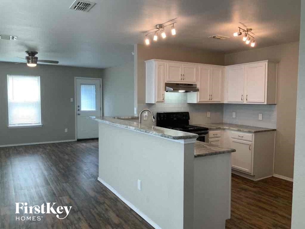 an empty kitchen with white cabinets and a counter top
