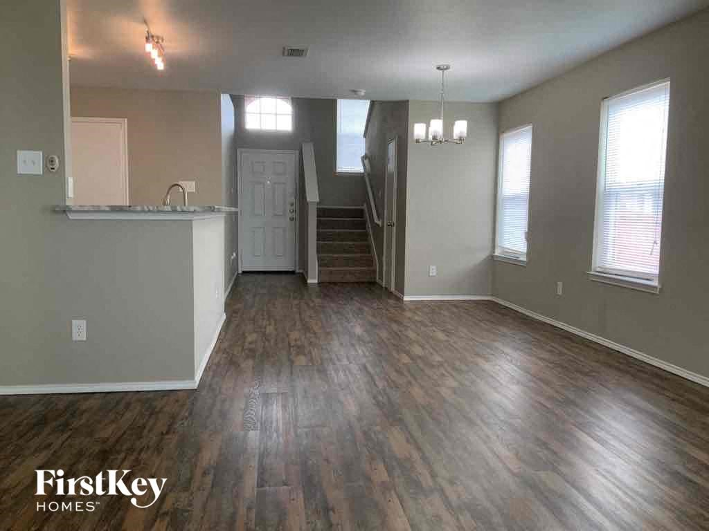 an empty living room with wood floors and a kitchen