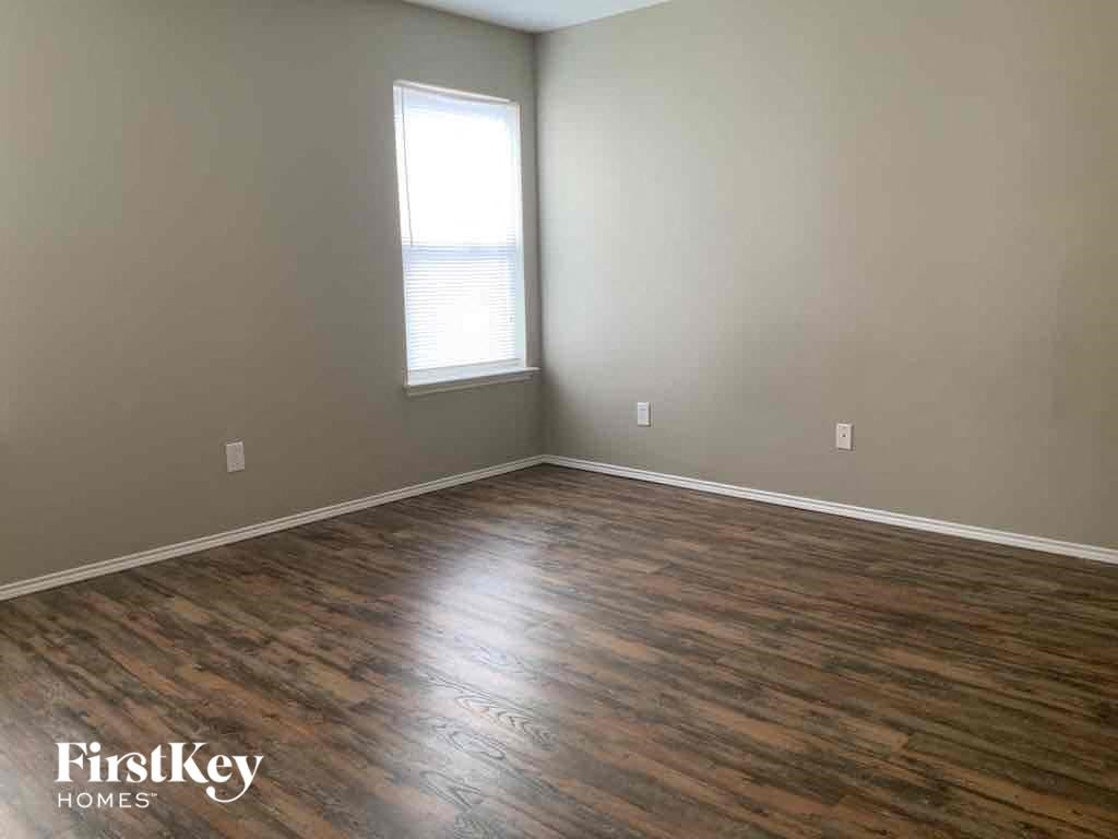 an empty living room with wood floors and a window