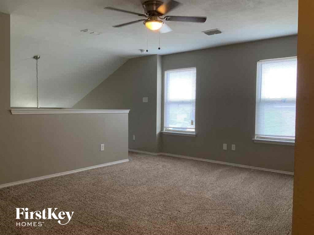 an empty room with a ceiling fan and two windows