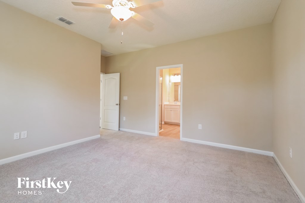 a spacious living room with carpet and a ceiling fan