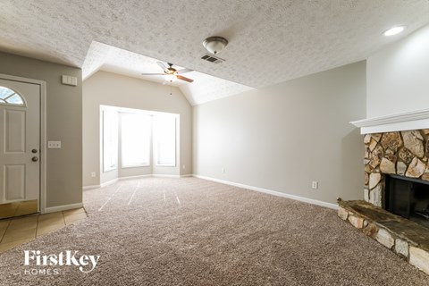 A spacious room with a fireplace and a carpet on the floor.