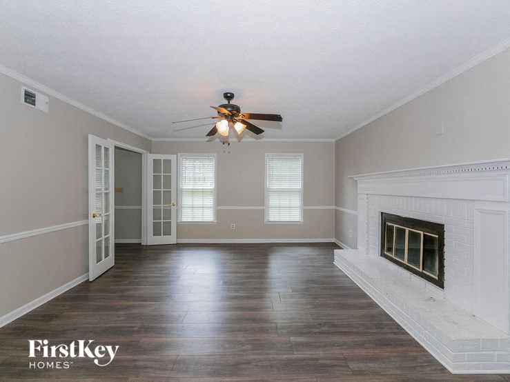 an empty living room with a ceiling fan and a fireplace
