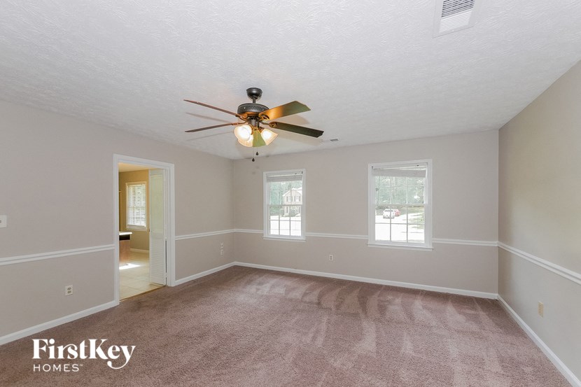 the spacious living room with ceiling fan and carpeting