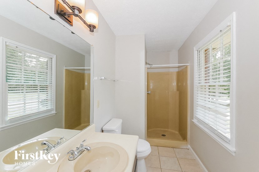 a bathroom with a shower sink and mirror and a toilet