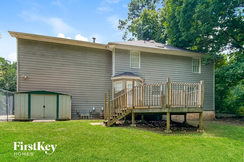 a backyard with a deck and a house and a green shed