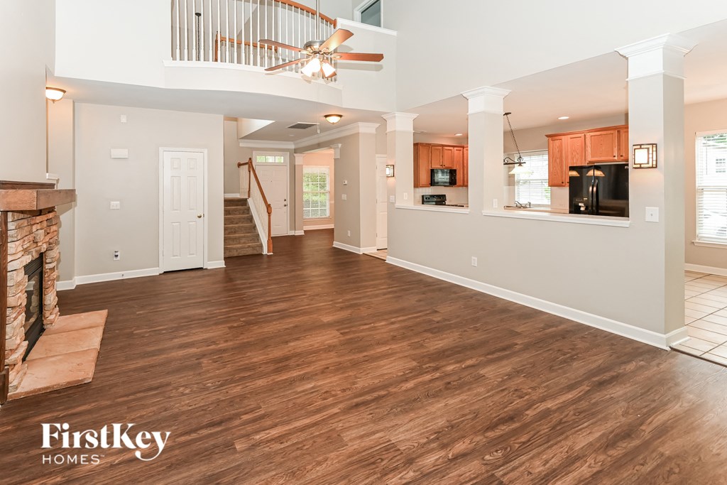 an empty living room with a fireplace and a ceiling fan