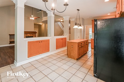 a large kitchen with a large island and a black refrigerator