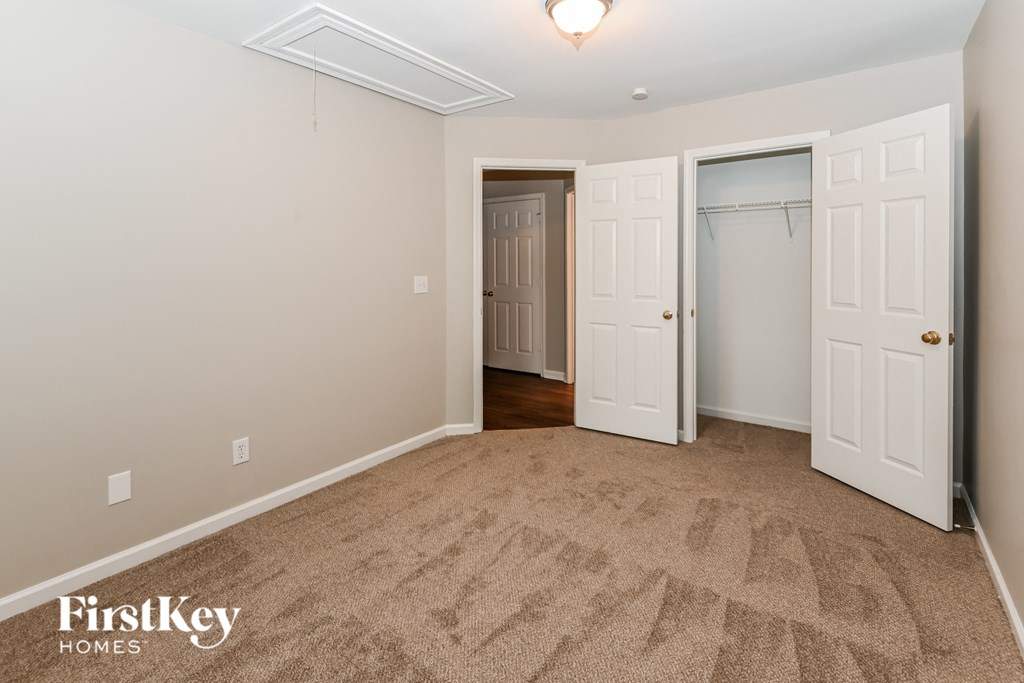 a bedroom with a carpeted floor and a closet with two doors