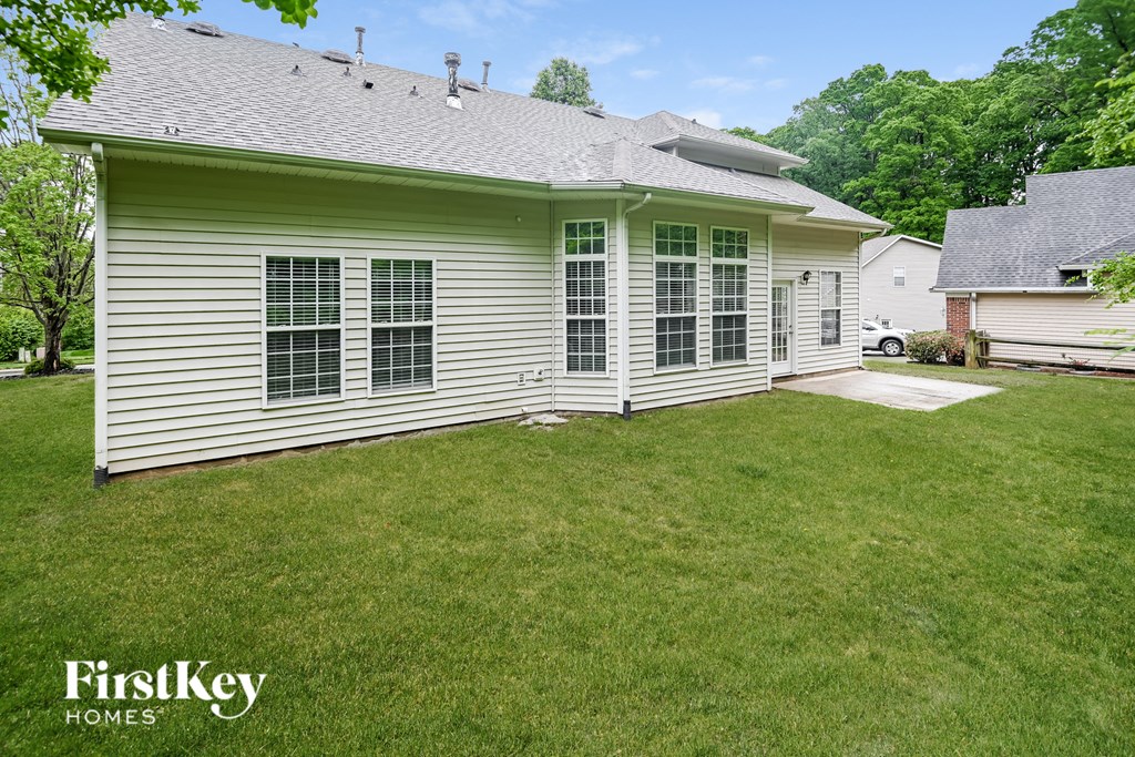 a backyard with a white house and a green lawn
