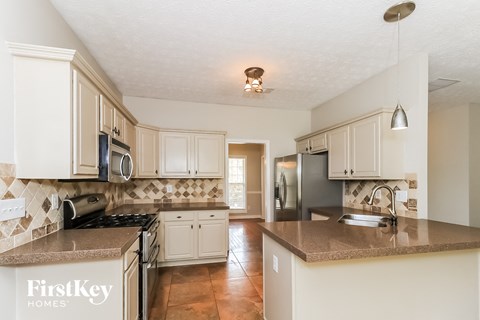 a kitchen with white cabinets and granite counter tops and a black refrigerator
