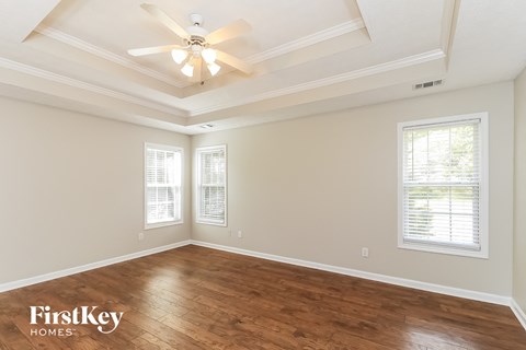 the spacious living room with hardwood flooring and a ceiling fan