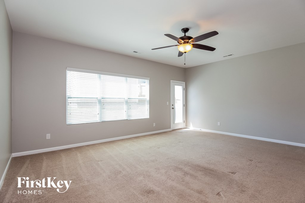 A spacious room with a ceiling fan and a window with blinds.