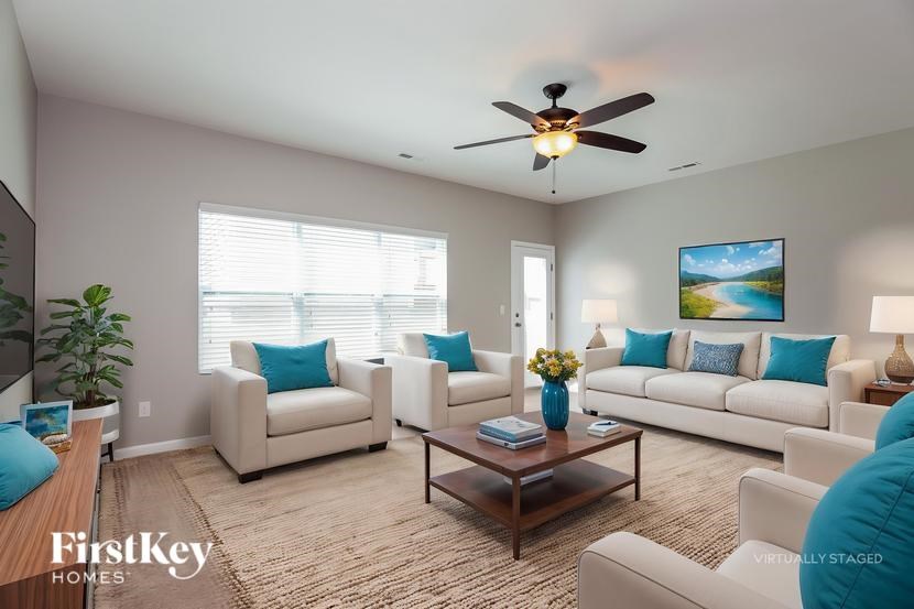 A living room with a ceiling fan and a painting on the wall.