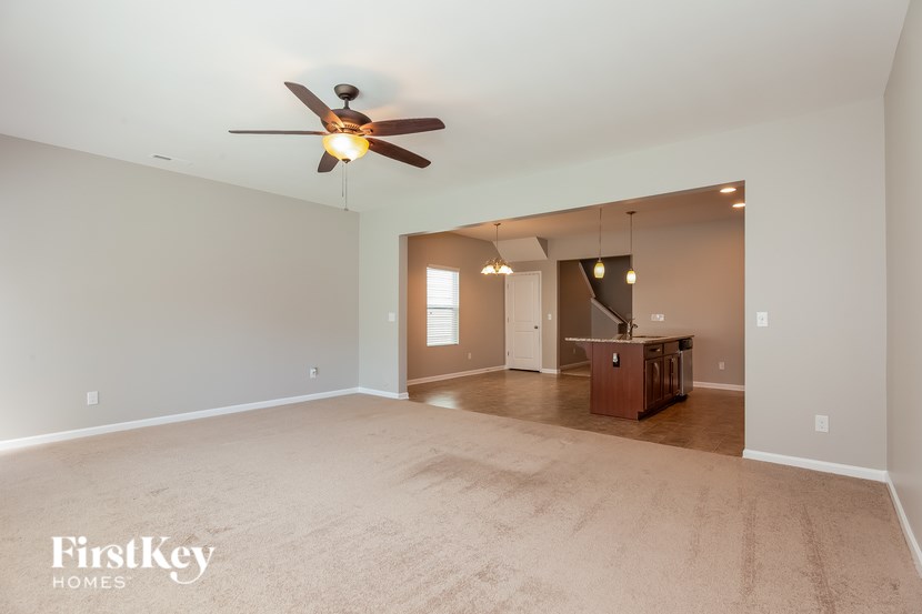 A spacious room with a ceiling fan and a carpeted floor.