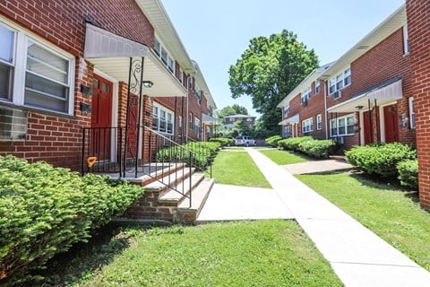 a sidewalk in front of a brick apartment building