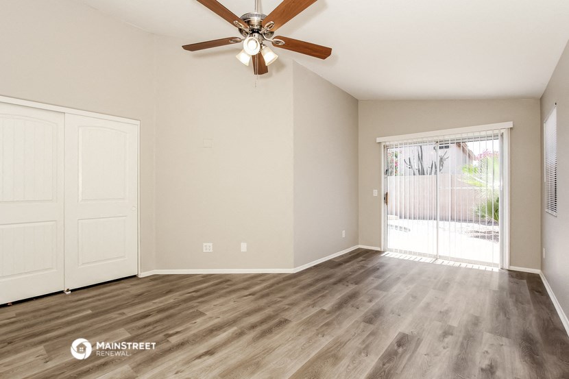 the spacious living room of an empty house with a ceiling fan