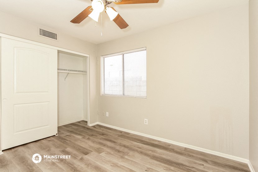 the spacious living room with a closet and a ceiling fan