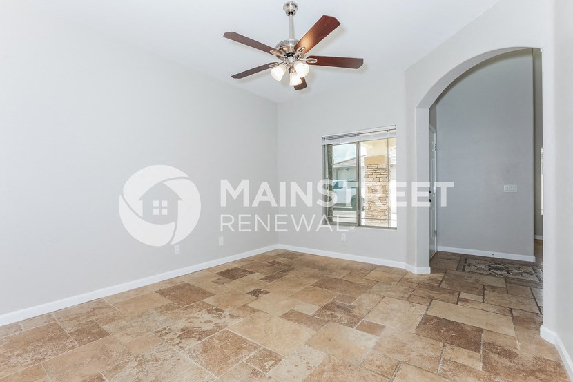 a living room with a large window and a ceiling fan