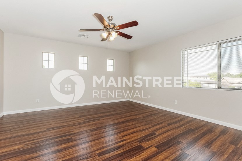 an empty living room with wood floors and a ceiling fan