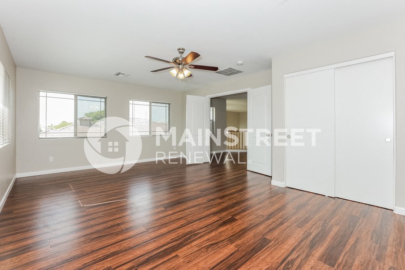 a renovated living room with wood floors and a ceiling fan