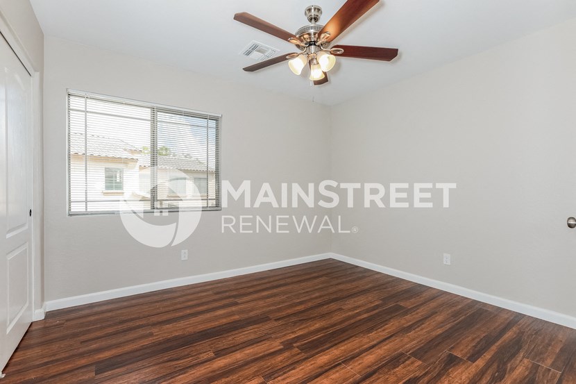 an empty living room with a ceiling fan and a window