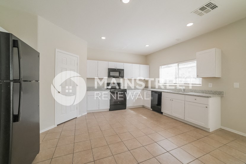 a renovated kitchen with white cabinets and a black refrigerator