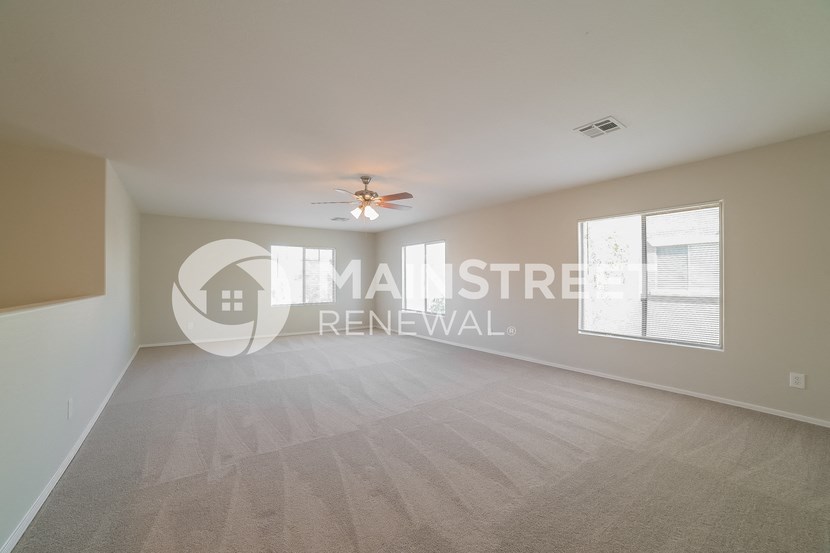 a spacious living room with a ceiling fan