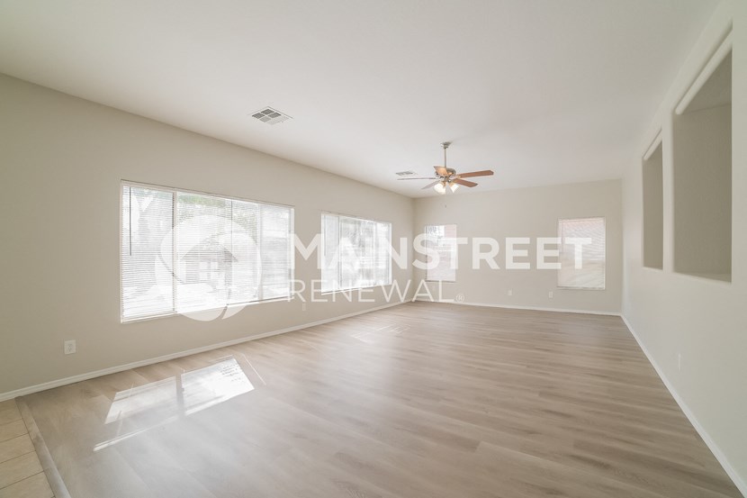 a empty living room with a ceiling fan and a large window