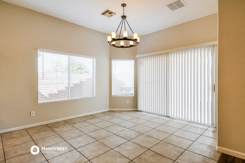 an empty living room with two windows and a chandelier