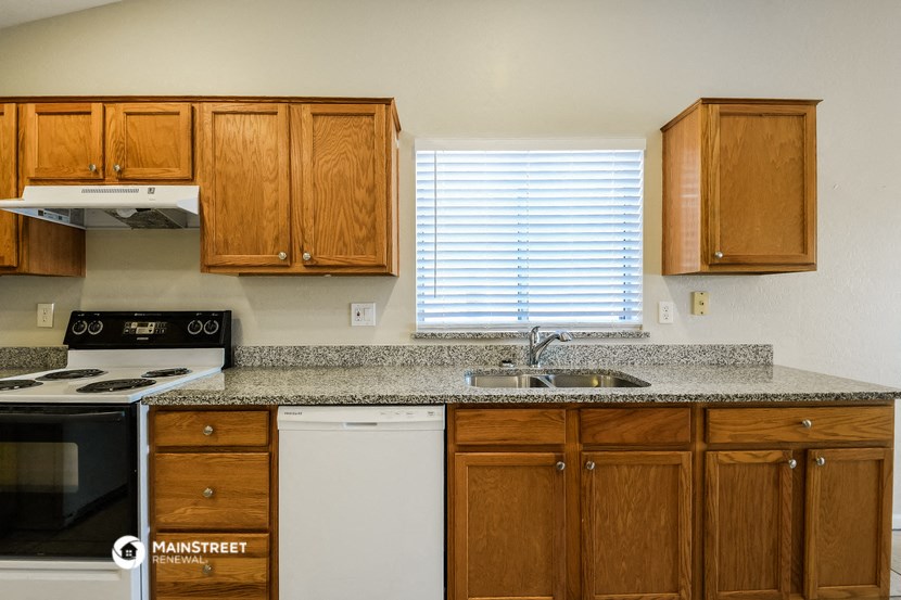 a kitchen with wooden cabinets and granite counter tops and a sink