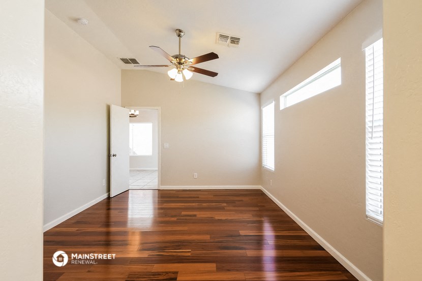 an empty living room with a ceiling fan and wood floors