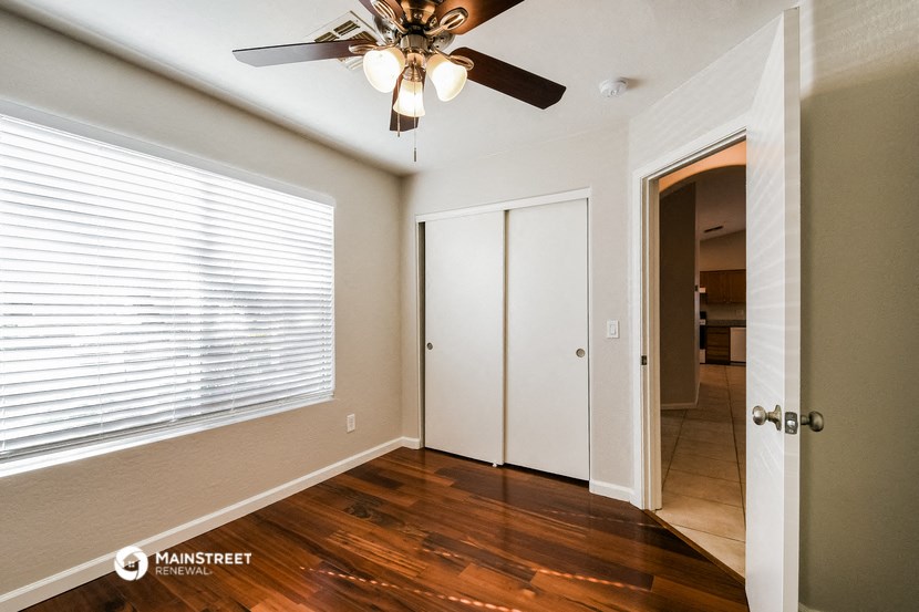 a bedroom with a large window and a ceiling fan