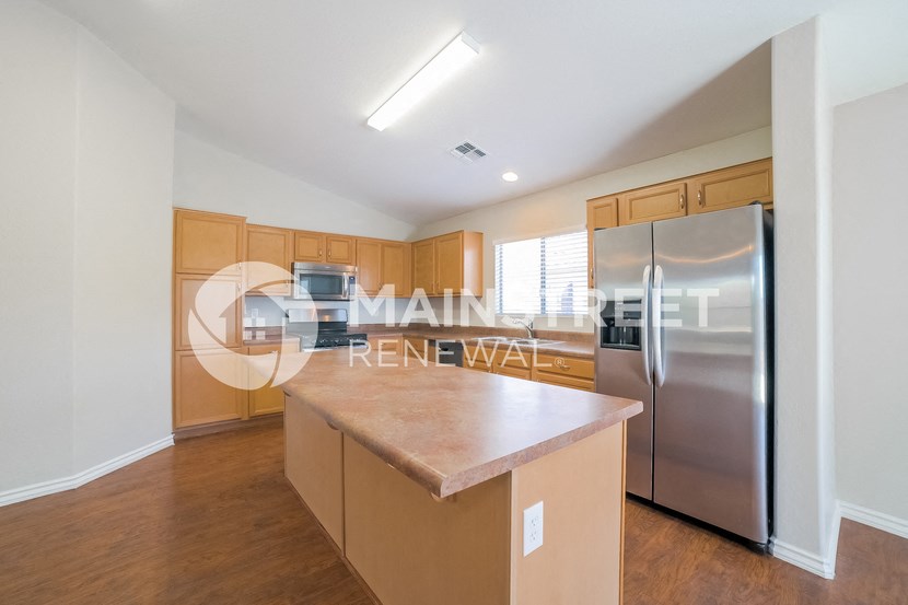 a kitchen with a large island and stainless steel refrigerator