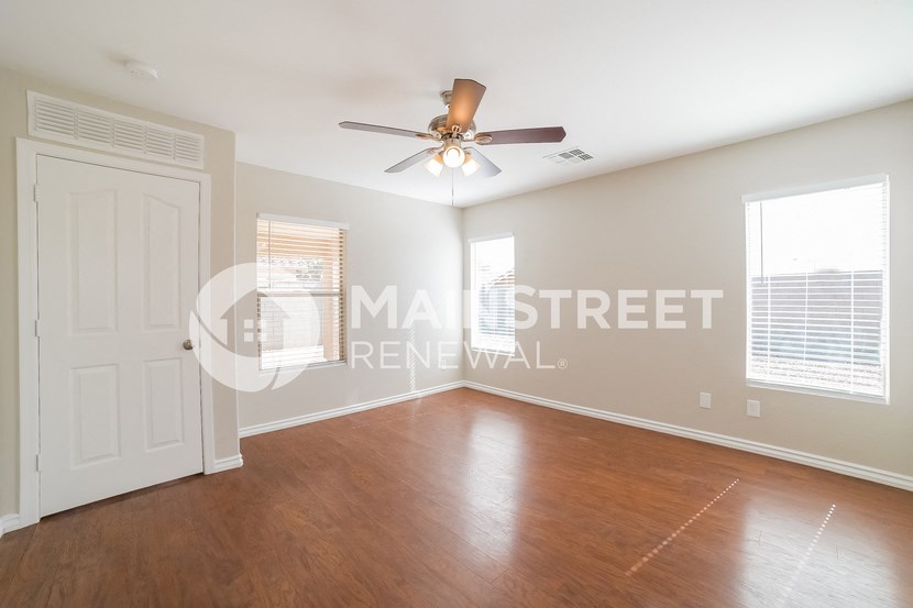 an empty living room with wood floors and a ceiling fan