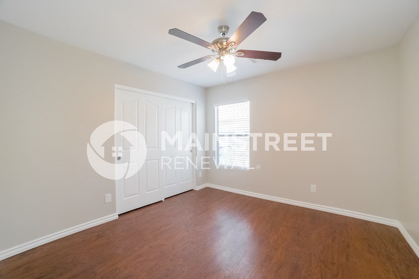 a bedroom with a wood floor and a ceiling fan