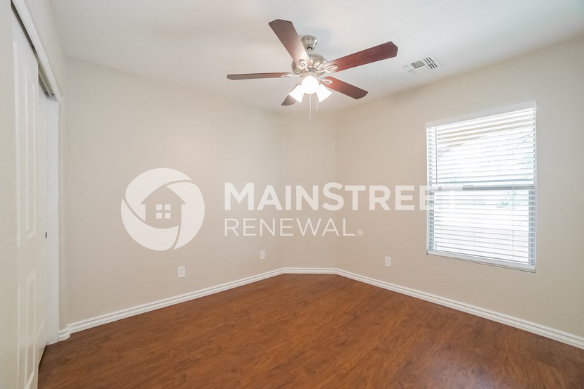 an empty living room with a ceiling fan and a window