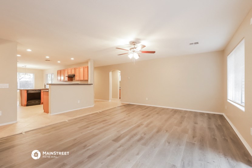 the spacious living room with wood flooring and a ceiling fan