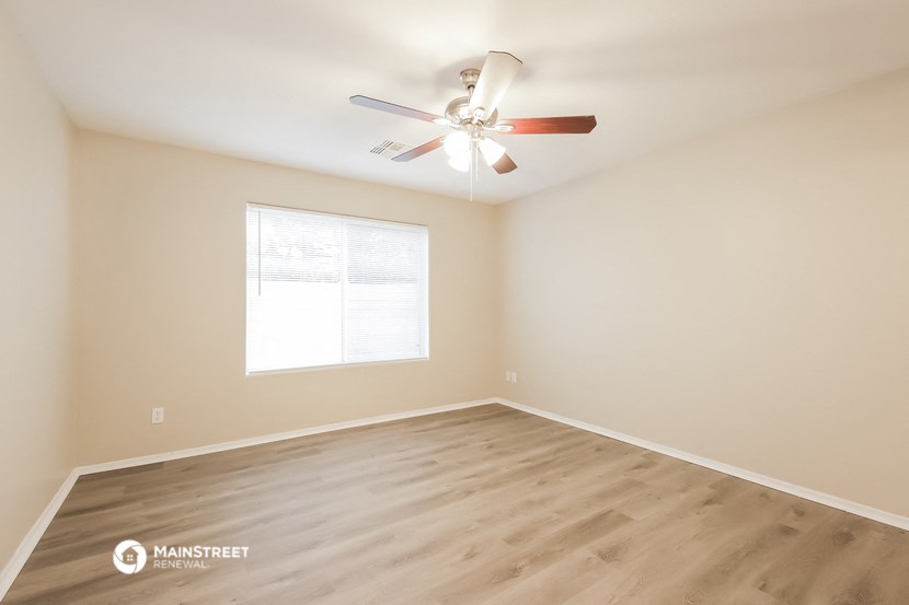an empty room with a ceiling fan and a window