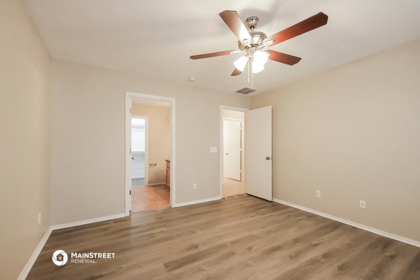 the spacious living room with ceiling fan and wood flooring