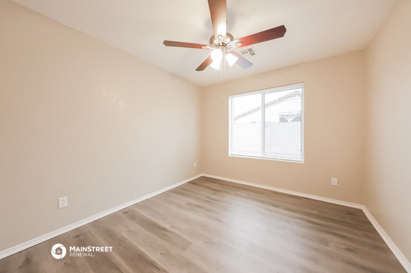 the spacious living room with wood flooring and a ceiling fan