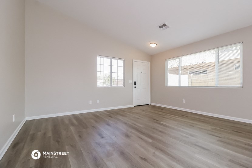 the spacious living room with wood flooring and a window